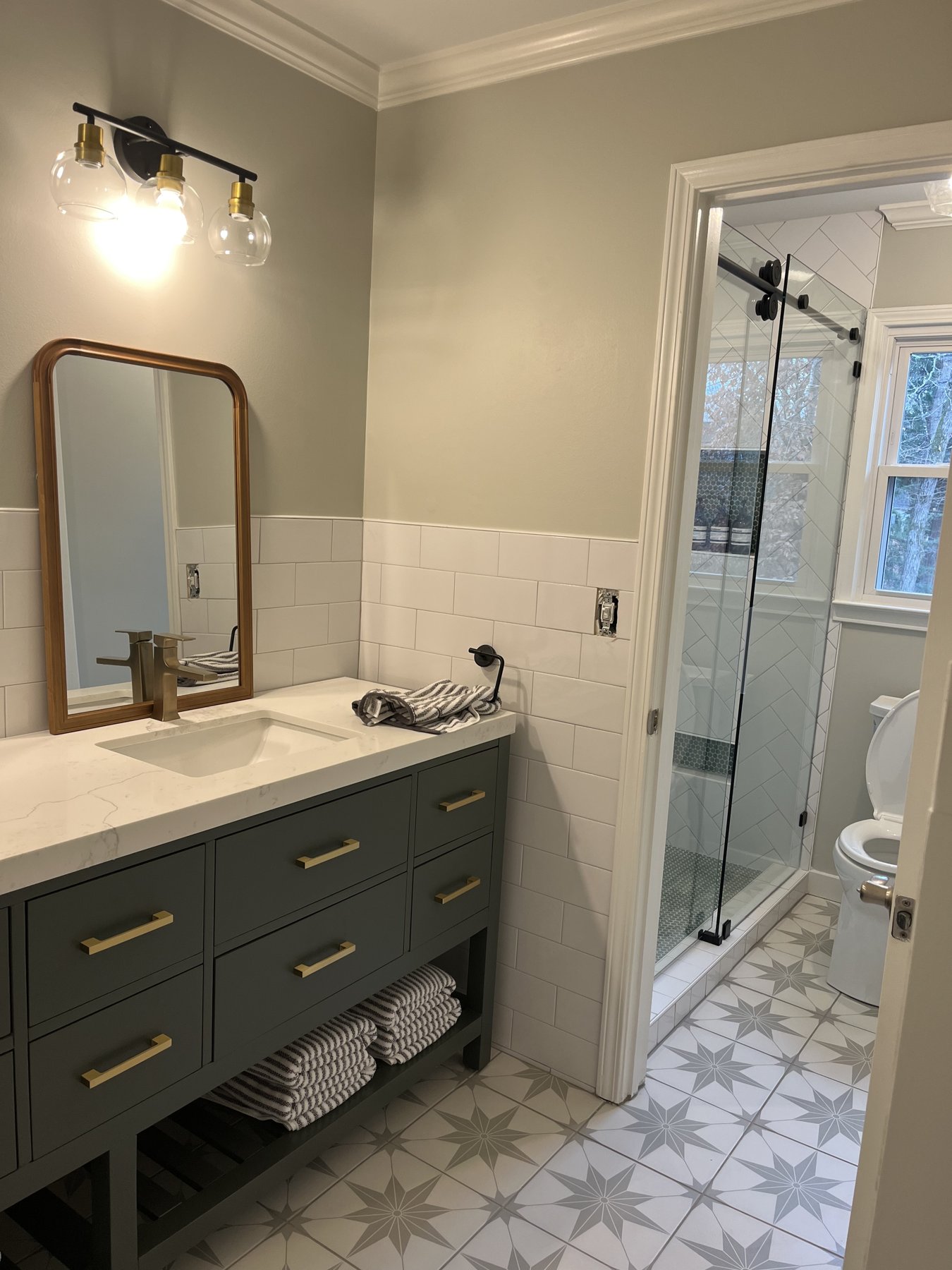 Primary bathroom with encaustic star-pattern floor, vertical-stack subway, herringbone marble shower.
