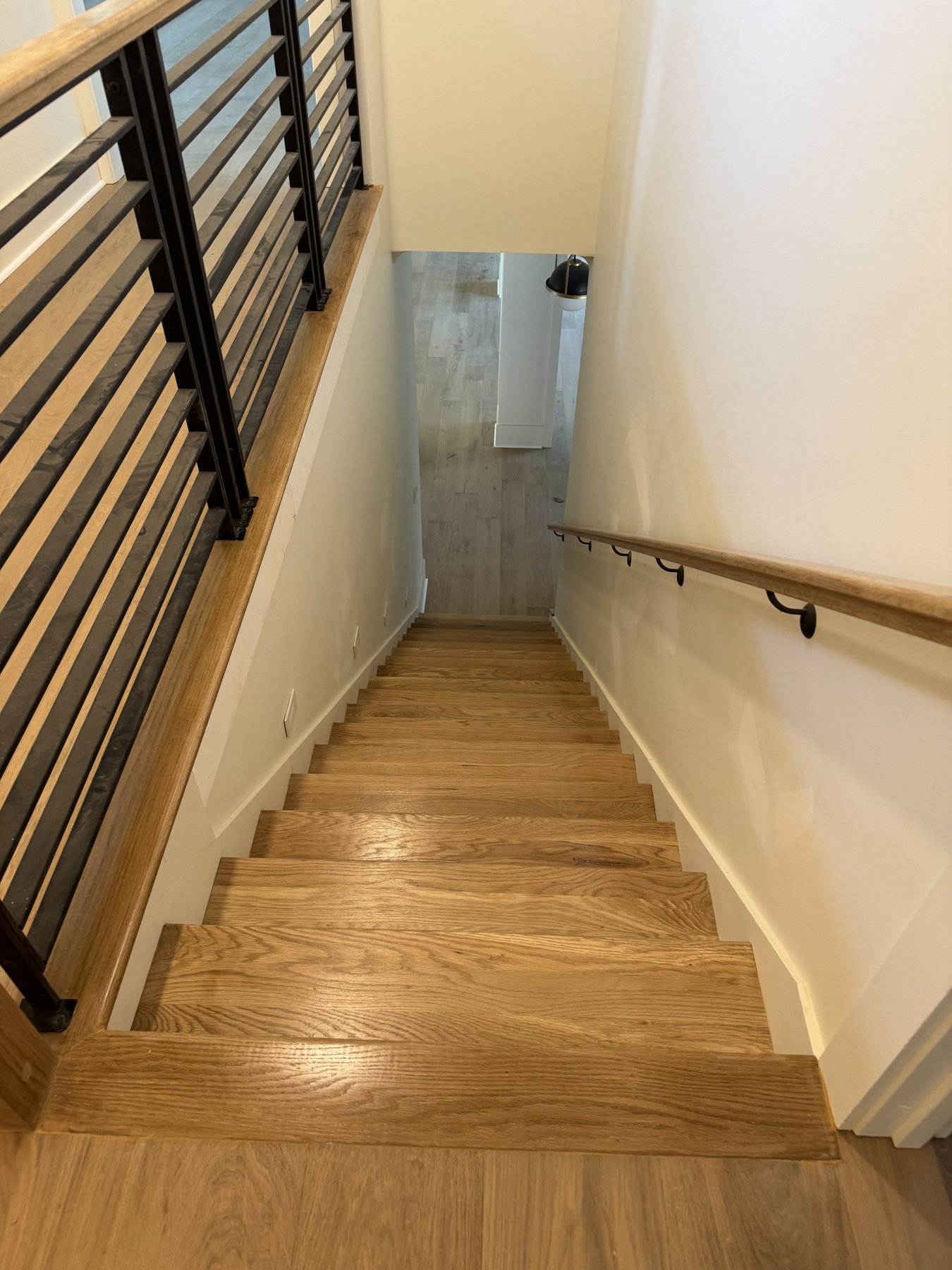 Solid white oak staircase with painted risers and black metal balustrade.